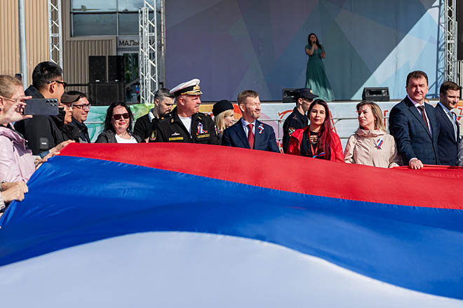 Длина полотнища российского флага составляла 16 метров, ширина – 9. Держали его в руках десятки человек, в том числе губернатор Чукотки Владислав Кузнецов и заместитель командующего Тихоокеанским флотом по военно-политической работе контр-адмирал Дмитрий Артёмов. ФОТО: ЗЕМФИРА АЗАМАТОВА Длина полотнища российского флага составляла 16 метров, ширина – 9. Держали его в руках десятки человек, в том числе губернатор Чукотки Владислав Кузнецов и заместитель командующего Тихоокеанским флотом по военно-политической работе контр-адмирал Дмитрий Артёмов. ФОТО: ЗЕМФИРА АЗАМАТОВА